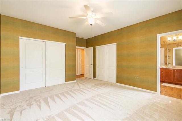 unfurnished bedroom featuring ensuite bathroom, ceiling fan, light colored carpet, and baseboards