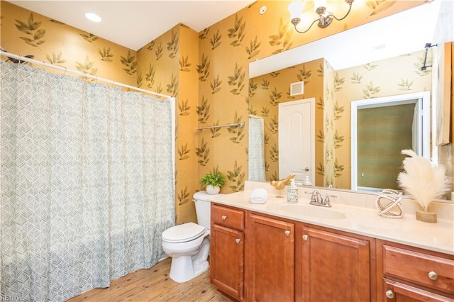 full bath featuring toilet, wood finished floors, vanity, and wallpapered walls