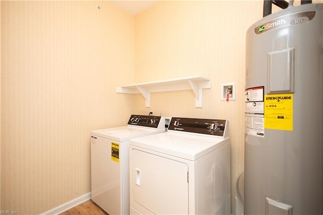 washroom featuring separate washer and dryer, laundry area, electric water heater, light wood-style floors, and baseboards