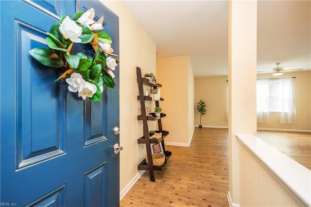 foyer entrance with a ceiling fan, wood finished floors, and baseboards