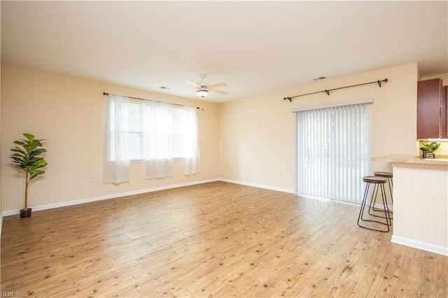 unfurnished living room featuring a ceiling fan, a healthy amount of sunlight, and light wood-style flooring