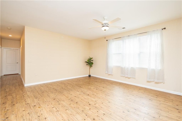 empty room with visible vents, ceiling fan, wood finished floors, and baseboards
