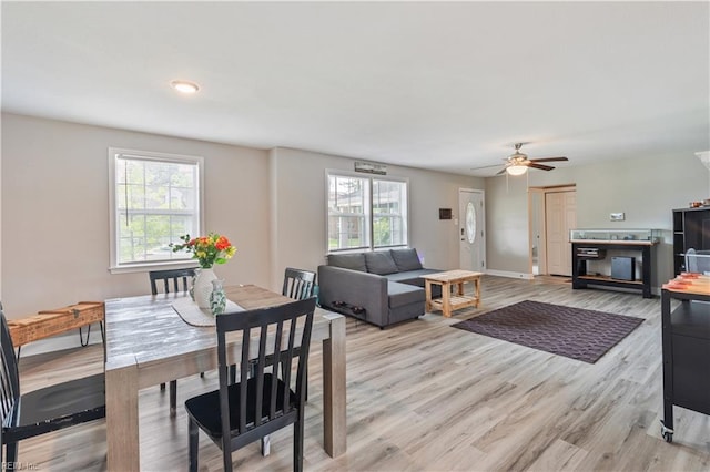 dining space featuring light wood-style floors, baseboards, and a ceiling fan