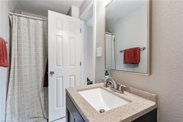 full bath featuring vanity, a textured wall, and a shower with shower curtain