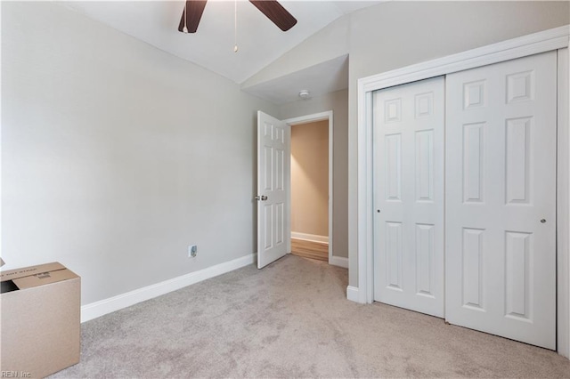 unfurnished bedroom featuring carpet flooring, a ceiling fan, baseboards, lofted ceiling, and a closet