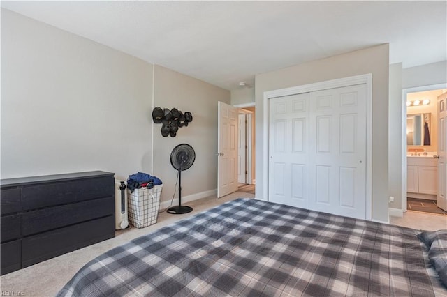bedroom with baseboards, ensuite bathroom, carpet, and a closet