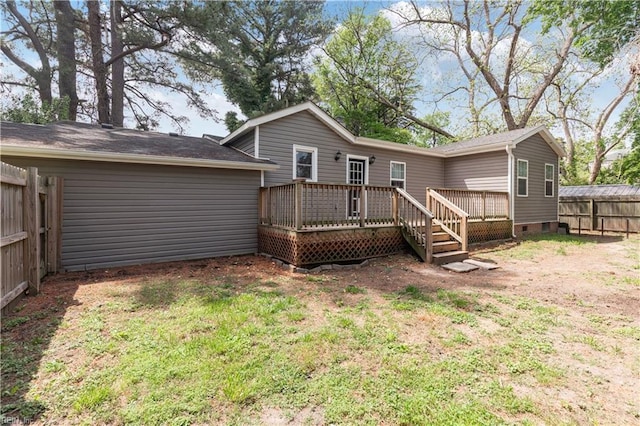 rear view of property with crawl space, a deck, fence, and a lawn