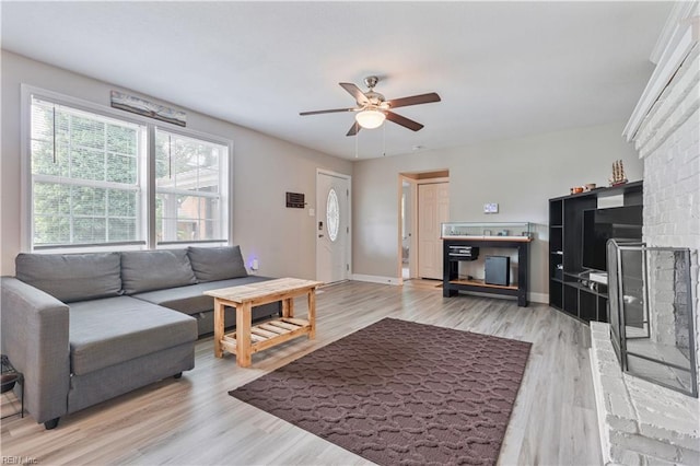 living area featuring ceiling fan, baseboards, and light wood finished floors