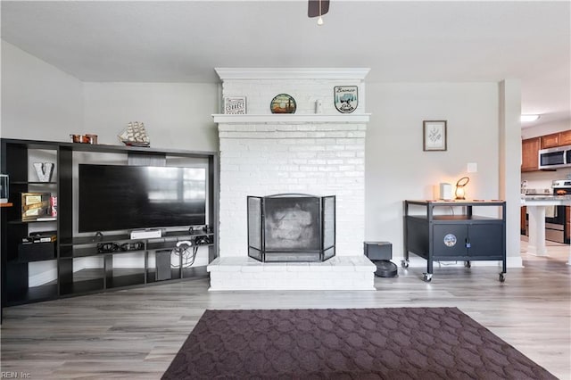 living area featuring a brick fireplace and wood finished floors