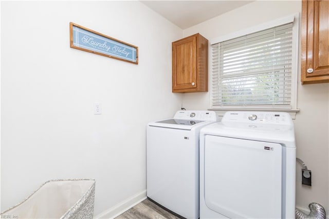 laundry area featuring cabinet space, baseboards, light wood finished floors, and washer and dryer