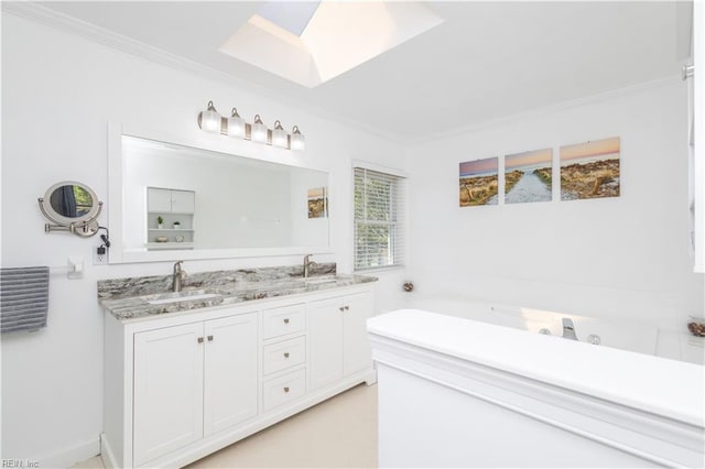 bathroom featuring crown molding, double vanity, a skylight, and a sink
