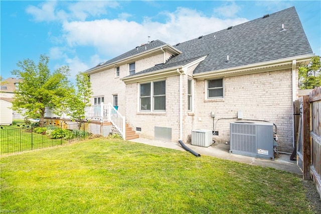 rear view of property featuring a yard, central AC unit, a fenced backyard, and roof with shingles