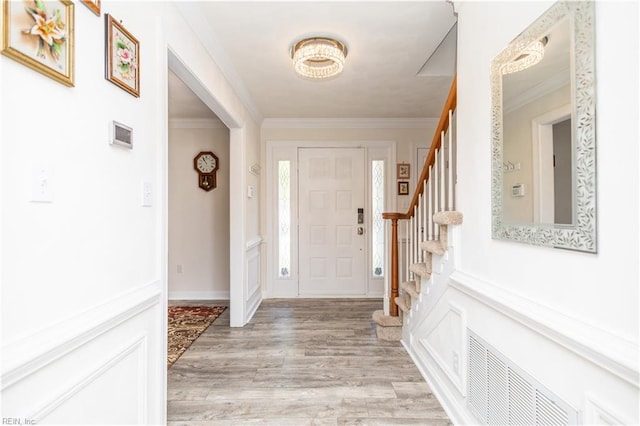 entrance foyer featuring stairs, visible vents, ornamental molding, and light wood finished floors