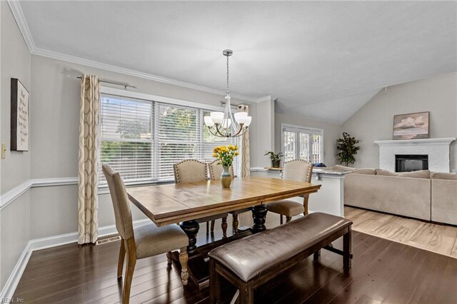 dining area with a glass covered fireplace, a wealth of natural light, dark wood finished floors, and a notable chandelier