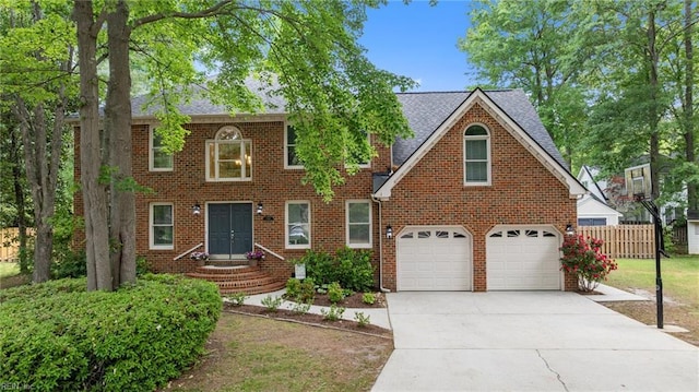 colonial home featuring fence, a shingled roof, driveway, and brick siding