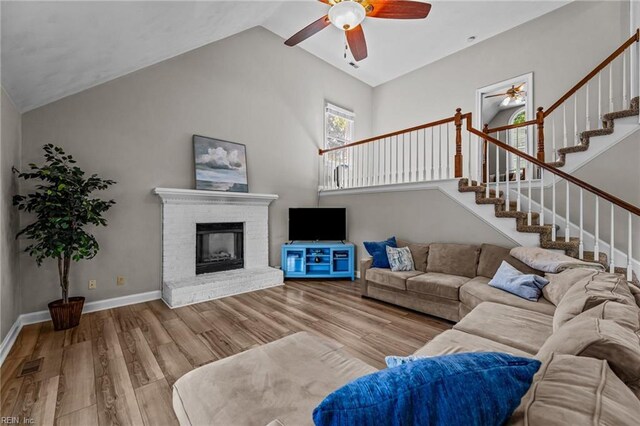 living area featuring visible vents, wood finished floors, ceiling fan, stairway, and vaulted ceiling