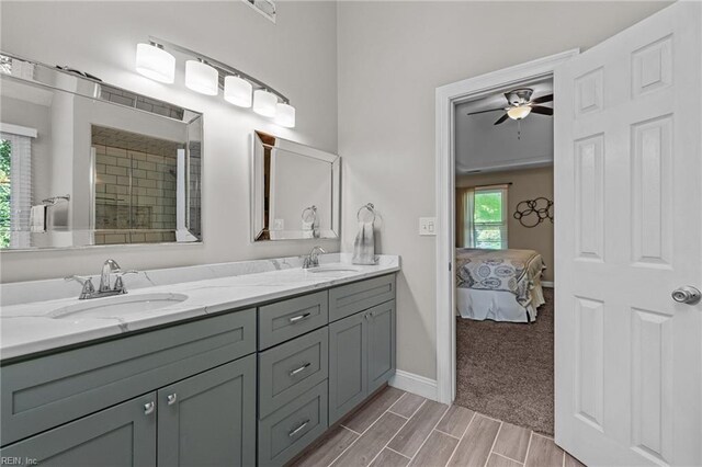ensuite bathroom featuring a sink, baseboards, a ceiling fan, and double vanity