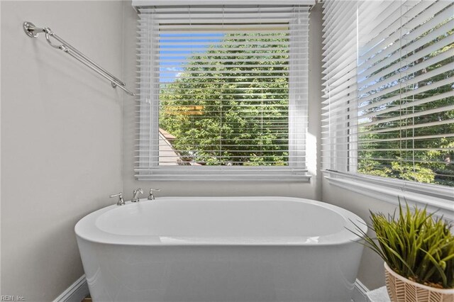 bathroom with baseboards, a freestanding bath, and a wealth of natural light