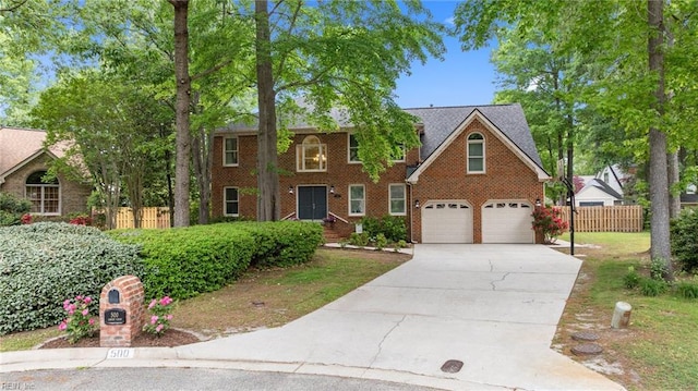 colonial-style house featuring fence, concrete driveway, brick siding, and a garage