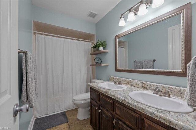 bathroom featuring visible vents, a sink, double vanity, and toilet