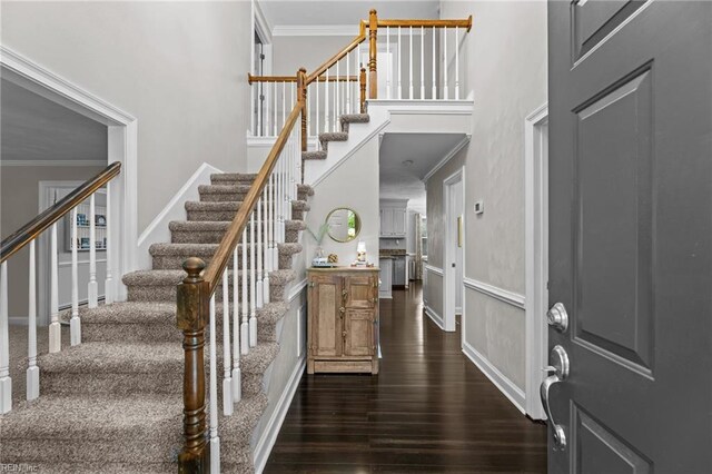 entryway with dark wood-style flooring, a high ceiling, baseboards, ornamental molding, and stairway