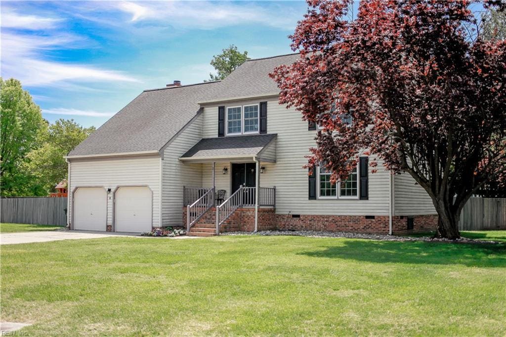 traditional-style home with driveway, a shingled roof, an attached garage, fence, and a front lawn