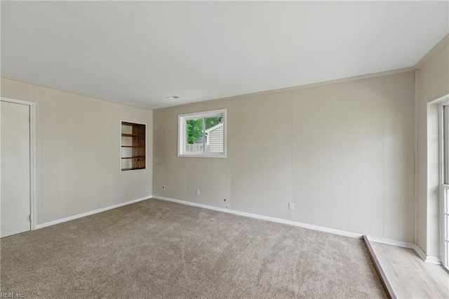 spare room with baseboards and light carpet