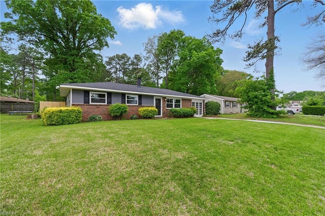 ranch-style house with brick siding, fence, and a front yard