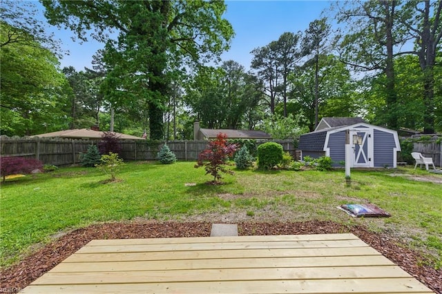 view of yard with a deck, a fenced backyard, a shed, and an outdoor structure