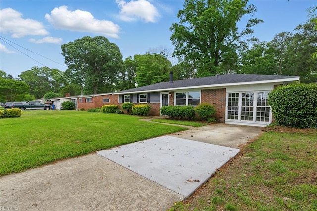 ranch-style house featuring brick siding, a front yard, and driveway