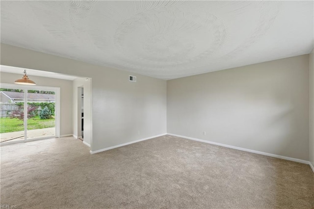 carpeted spare room featuring visible vents and baseboards