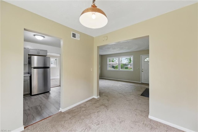 carpeted empty room with visible vents and baseboards