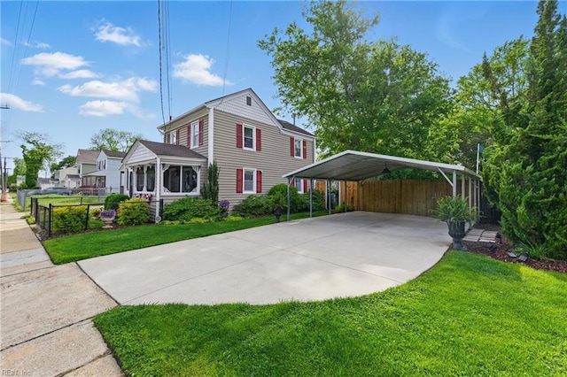 view of front of property featuring driveway, fence, a detached carport, and a front yard