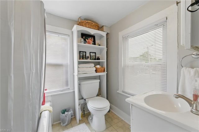 full bath with baseboards, tile patterned floors, toilet, and a sink