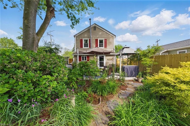 back of property featuring fence and a gazebo