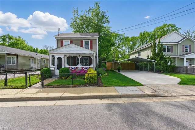 view of front of home with concrete driveway, a detached carport, a front yard, and fence private yard