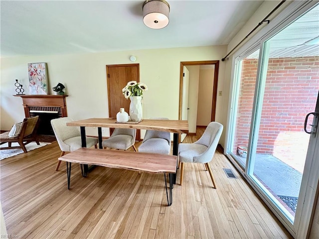 dining space with a fireplace, visible vents, and light wood-type flooring