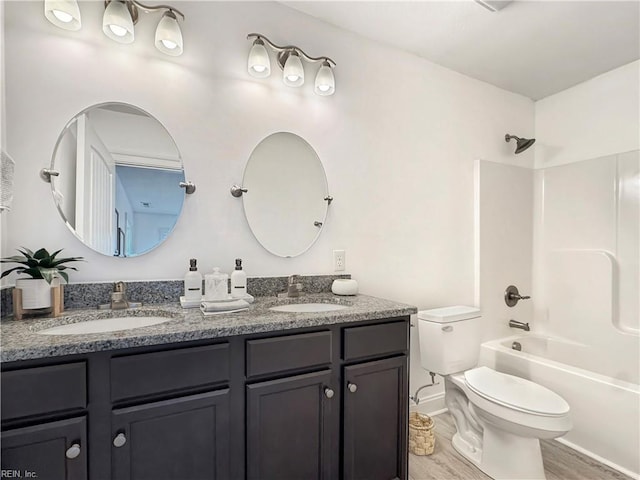 bathroom with double vanity, shower / washtub combination, toilet, and a sink