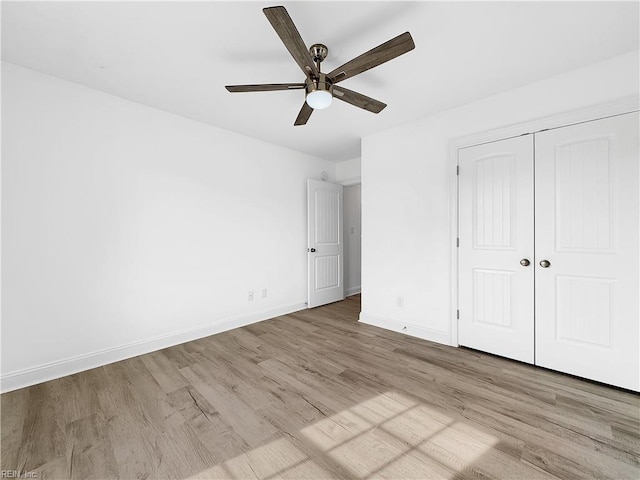 unfurnished bedroom with baseboards, wood finished floors, ceiling fan, and a closet