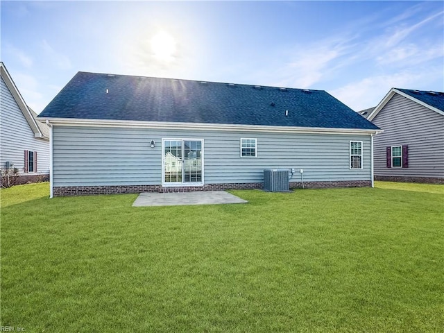 back of property featuring a lawn, roof with shingles, central air condition unit, and a patio