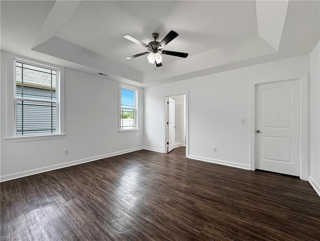 unfurnished bedroom featuring visible vents, baseboards, a raised ceiling, and dark wood-type flooring