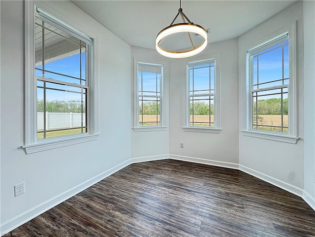 unfurnished dining area featuring dark wood finished floors and baseboards
