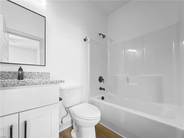 full bath with wood finished floors, toilet, shower / bathtub combination, vanity, and baseboards