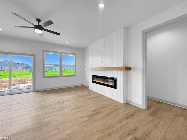 unfurnished living room featuring recessed lighting, a large fireplace, and light wood-type flooring
