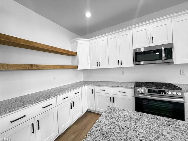 kitchen with dark wood finished floors, light stone counters, stainless steel appliances, open shelves, and white cabinetry