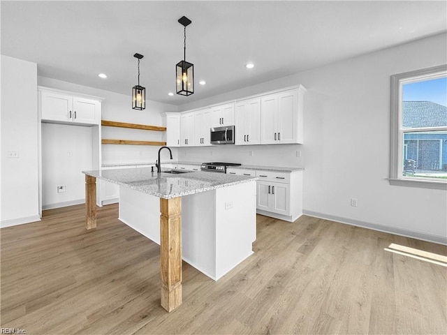kitchen featuring recessed lighting, open shelves, appliances with stainless steel finishes, light wood finished floors, and a sink