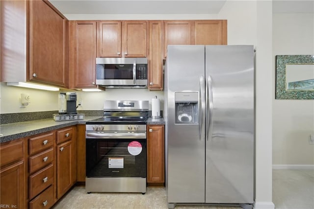 kitchen featuring dark countertops, stainless steel appliances, and brown cabinets