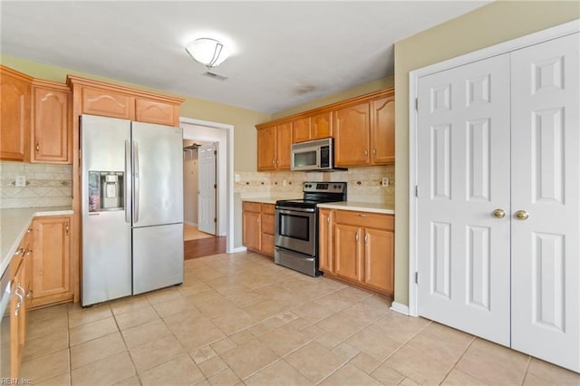 kitchen featuring light countertops, visible vents, stainless steel appliances, and decorative backsplash