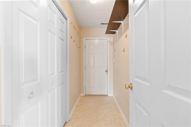 corridor featuring baseboards, visible vents, and light floors