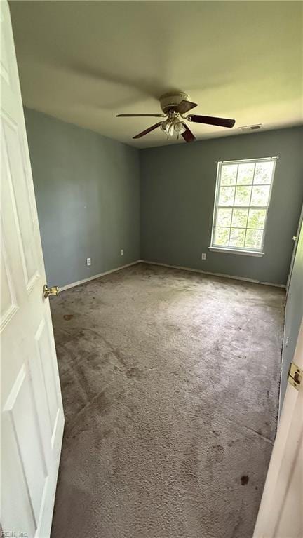 spare room featuring baseboards, ceiling fan, and carpet